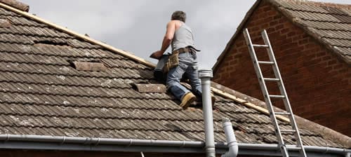 Contractor on tile roof repairing tile